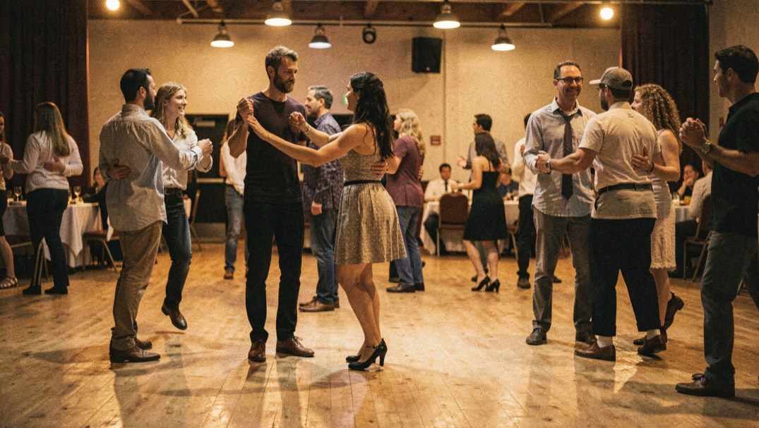 Dancers share a busy floor with clear spacing, relaxed arms and awareness of nearby couples under amber lights.